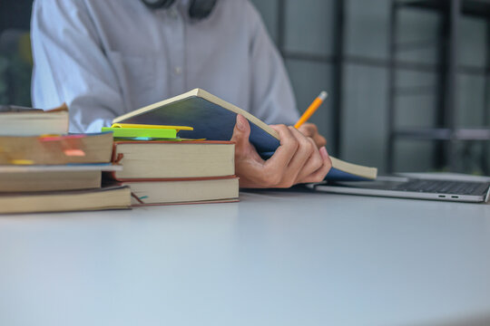 College Student Writing Research Notes During Online Learning and Academic Study Session at Home.