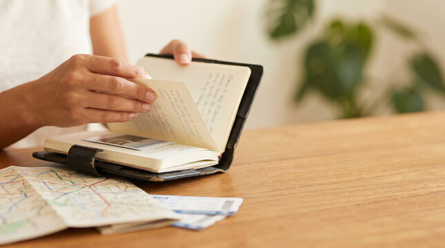 Woman Hands Flipping Through Travel Journal Notebook Near Map and Airline Tickets on Wooden Table, Female Backpacker Planning Vacation Journey and Memories with Copy Space
