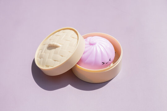 Dumpling toy in a container placed on a light purple background during daytime