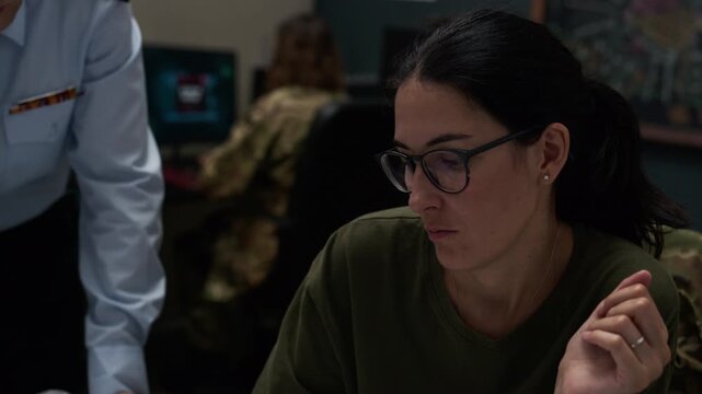 Caucasian male officer and female specialists analyzing tactical map and computer screen showing mission failure under red emergency lights. Footage ideal for defense industry videos