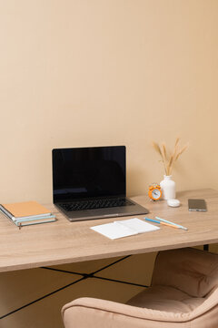 Workspace with a laptop and stationery on a desk in a simple room setting