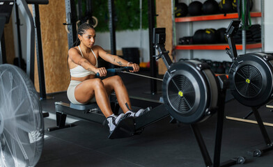 Fototapeta premium Young woman training core body on rowing machine
