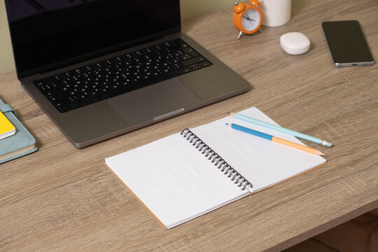 Workspace with laptop and notepad on wooden desk during daytime