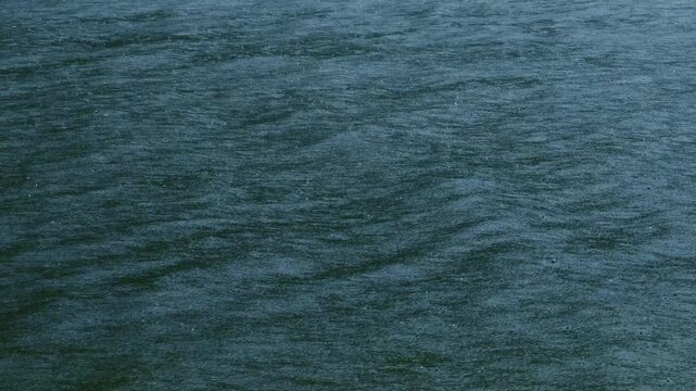 Heavy rain falling on dark lake water surface