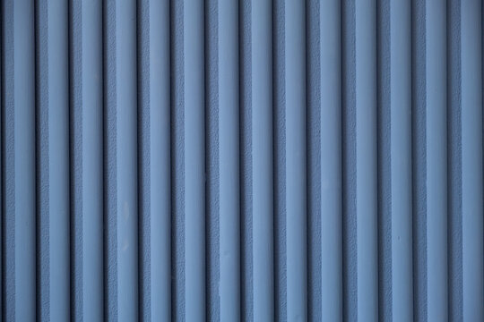 Vertical blue lines create a textured pattern on a wall in a modern indoor space during daylight