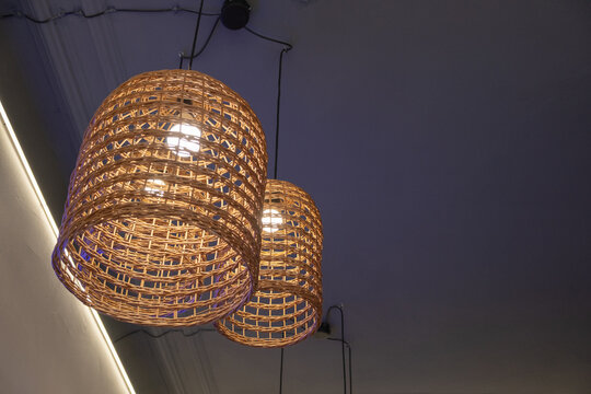 Two woven pendant lights hang from the ceiling in a cafe during the evening