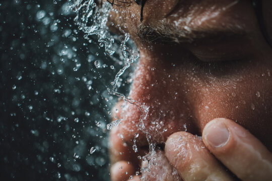 Close-up of a person splashing water on their face with a refreshing water spray
