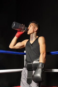 Hispanic boxer drinking water from reusable bottle in ring corner