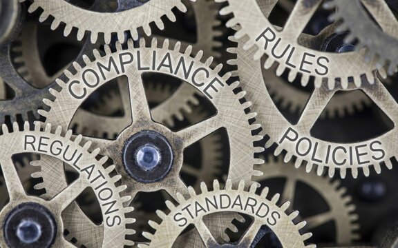 Brass gear mechanism with engraved words compliance, rules, policies, and standards