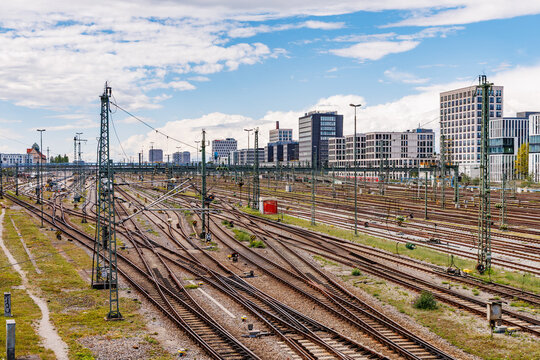 Aerial view of intricate railway track network and overhead catenary system with modern city skyline in Munich, urban transport and logistics concept