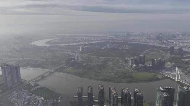Aerial drone view of Thu Thiem, Saigon River and Ba Son Bridge, with Bitexco Financial Tower in Ho Chi Minh City, Vietnam, illuminated by bright sunlight over the modern urban skyline.