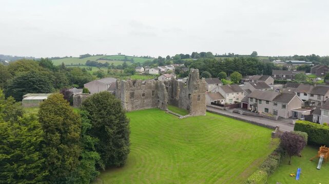 Low aerial view of the Castle Caulfield ruins framed by trees with Castlecaulfield village and the Tyrone countryside beyond, Northern Ireland