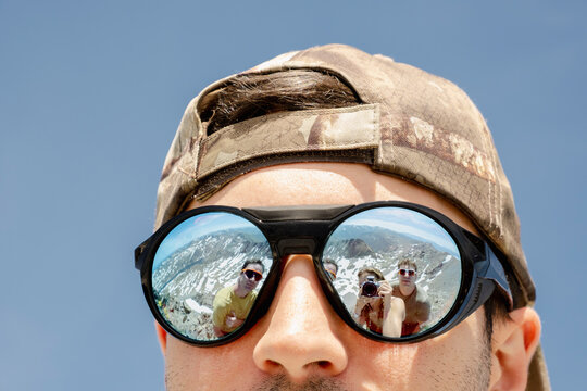Reflection of friends in sunglasses on Pyrenees mountain summit