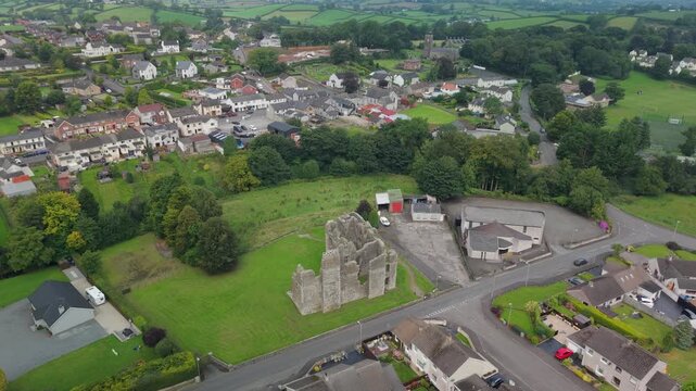 Aerial descent towards the ruins of Castle Caulfield above the streets of Castlecaulfield village, County Tyrone, Northern Ireland