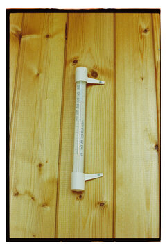 Thermometer attached to wooden wall in indoor setting