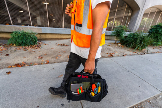 construction worker in orange safety vest walking with tools