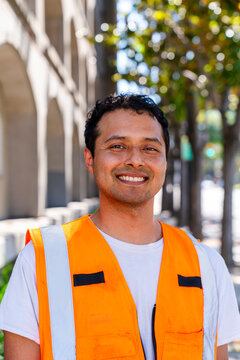 headshot of construction worker in orange safety vest smiling