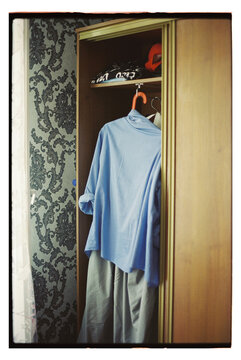Clothes stored in a wooden wardrobe with a patterned wall