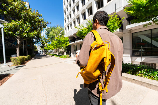 casual man walking to work sidewalk office buildings