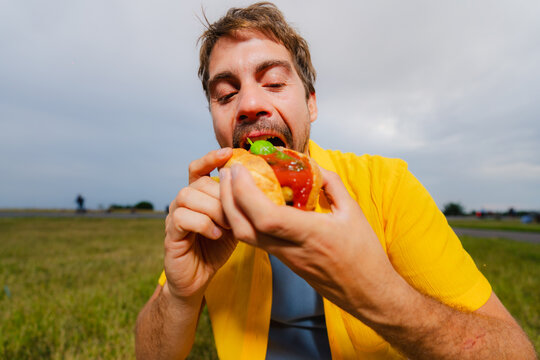 Man Biting Into Burger Outdoors