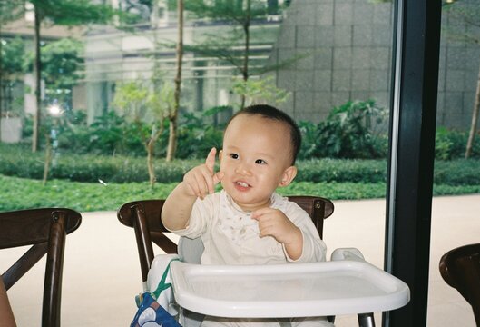 Happy toddler pointing finger while sitting in a high chair