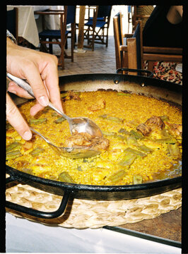 Hands serving traditional Spanish paella in restaurant