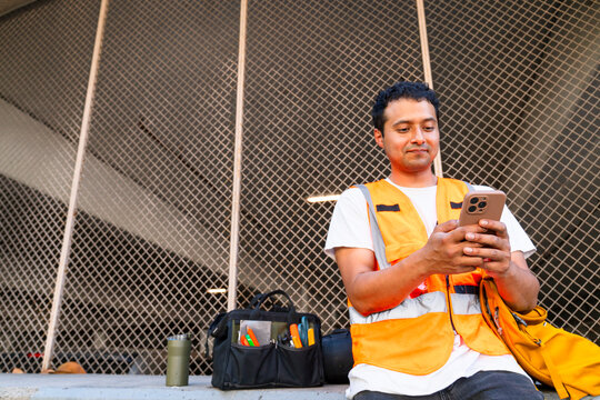 construction worker sitting on break using mobile phone