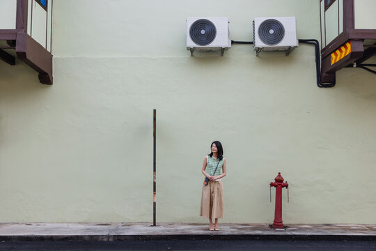 Young Woman Standing Against Minimal Urban Wall with Red Fire Hydrant