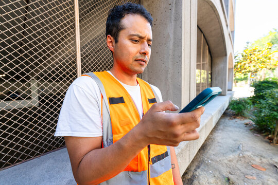 construction worker by parking garage using mobile phone confused