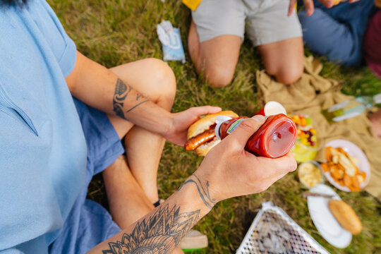 Adding Ketchup to Picnic Sausage Sandwich