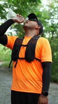 Man drinking water during a trail run in a mountain forest. Outdoor fitness, hydration, endurance and personal challenge while pursuing health goals and an active lifestyle.
