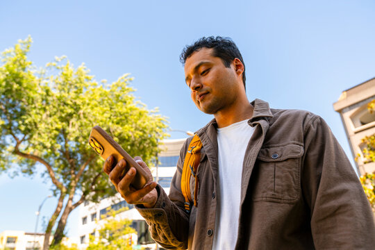 candid casual man using cellphone outside downtown low angle