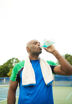 Black man hydrating after playing tennis
