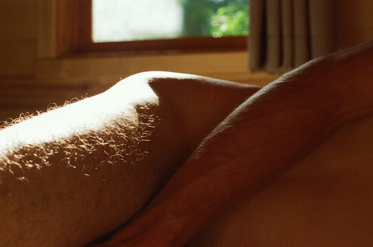 View of a masculine body lying in a bed in sunlight 