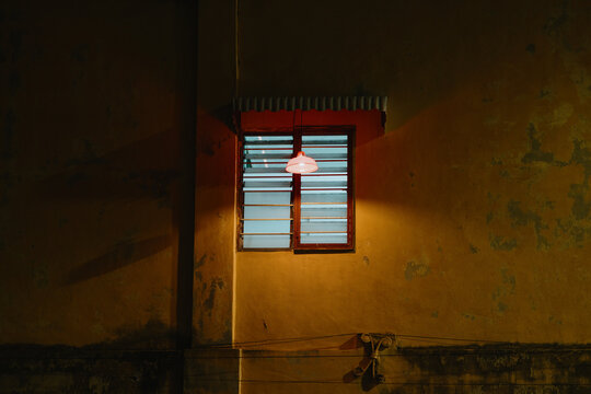 Illuminated Window on Weathered Building Wall at Night