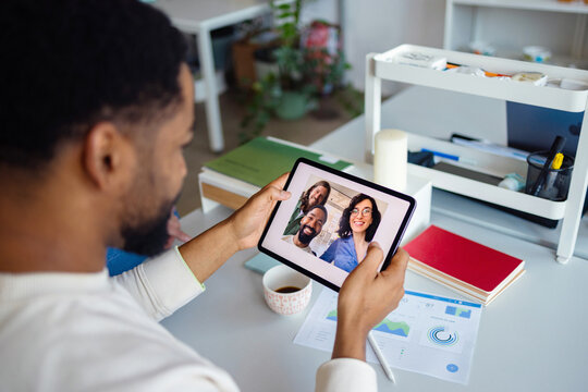 Man Video Calling Colleagues On Tablet During Workday