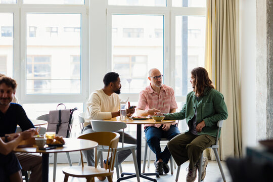 Three Men Talking Over Lunch In Bright Cafe