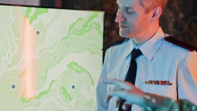 Soldier using tablet with map, camera tilting up to Caucasian middle aged military officer reviewing documents in command center. Clip is ideal for defense technology and national security videos