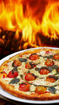 Freshly baked pizza with cherry tomatoes, melted cheese, and pesto sauce, against a blazing fire background.