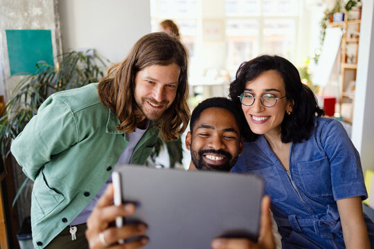 Happy Coworkers Looking at Tablet in Office
