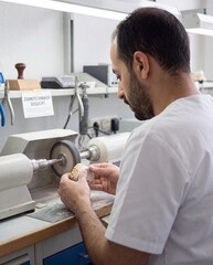 Fototapeta premium Zahntechniker gesucht Mann poliert Zahnersatz im Dentallabor