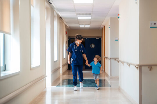 Pediatrician walking young boy patient in hospital