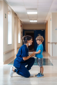 Doctor reassuring child patient in hospital corridor