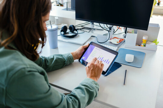 Businessman Reviewing Analytics On Tablet At Office