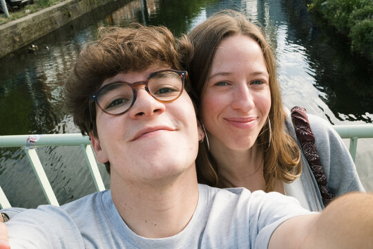 Young couple takes selfie on bridge over water in summer