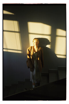 Woman walks down stairs in warm light with long shadows