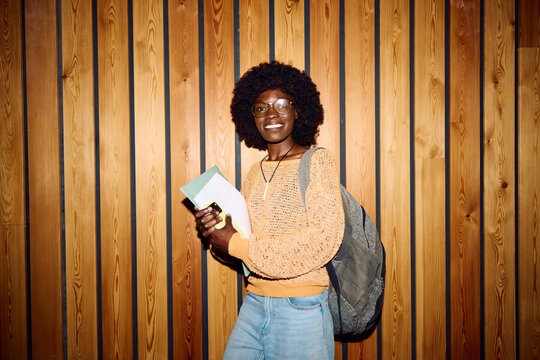 Student Stands Near Wooden Wall And Smiling