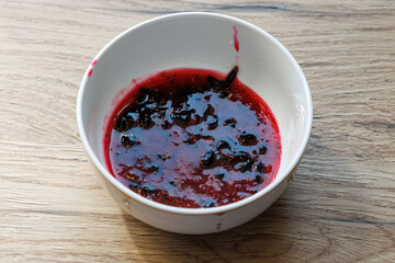 Red berry compote sits in a white bowl © schankz