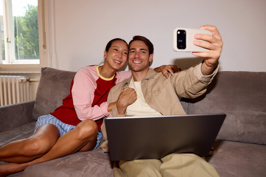 Couple takes selfies on a couch.