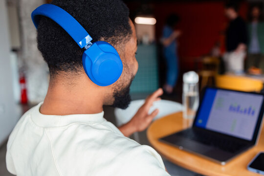 Man Wearing Blue Headphones Working On Laptop